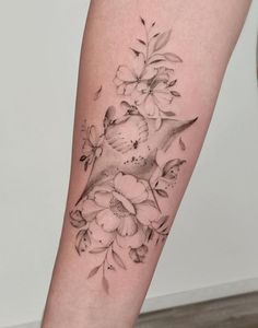 a woman's leg with flowers and a bird tattoo on the left side of her arm