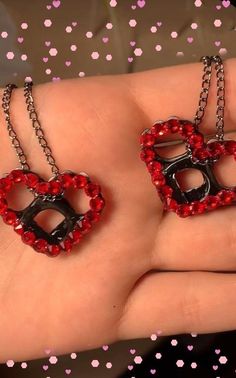 two red heart shaped pendants on a hand