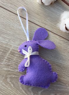 a purple bunny ornament sitting on top of a wooden floor next to cotton balls