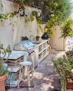 an outdoor kitchen with potted plants and stools