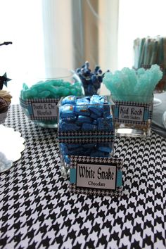 blue and green candies are in glass containers on a black and white tablecloth