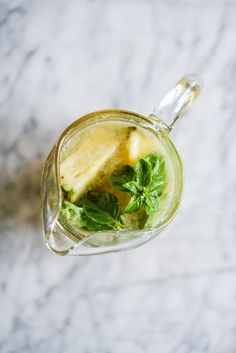 a glass filled with lemon and mint on top of a table