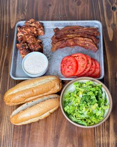 an assortment of meats and vegetables on a tray with bread, tomatoes, lettuce