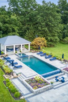 an aerial view of a backyard with a pool and lounge chairs in the foreground