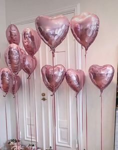 a bunch of pink heart shaped balloons hanging from the side of a white door in a room