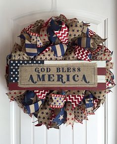 a patriotic wreath with the words god bless america on it hanging from a white door