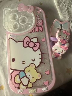 a hello kitty cell phone case next to a pacifier and toothbrush holder on a bed