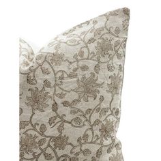 a white and brown pillow with an intricate design on the front, sitting against a white background