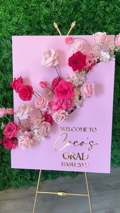 a welcome sign with pink flowers and greenery in the background for a wedding or bridal party