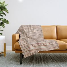 a couch with a blanket on it next to a potted plant