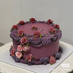 there is a purple cake with pink flowers on the top and bottom, sitting on a white plate