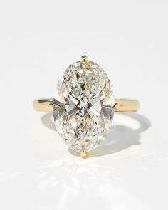 an oval cut diamond in yellow gold setting on a white surface with the center stone missing