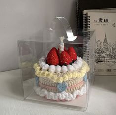 there is a cake with strawberries on it in the glass case next to books