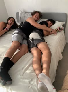 two men and a woman laying on a bed