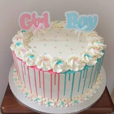 a birthday cake with white frosting and blue icing dripping down the side, on a wooden stand