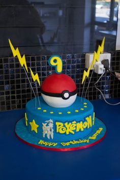 a pokemon themed birthday cake with lightning and pikachu on the top, sitting on a blue table