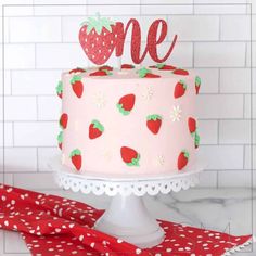 a strawberry themed cake with the word one on top