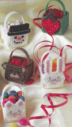 crocheted baskets with candy in them on a white cloth covered table next to red ribbon