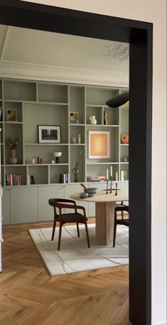 a dining room table and chairs in front of bookshelves with shelves on the wall