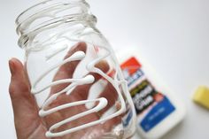 a hand holding a glass jar filled with liquid