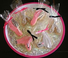 pink and white decorated cookies in plastic bags on top of a plate with hairbrushes