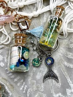 three glass bottles filled with different items on top of a lace covered table cloth,