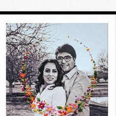 a man and woman standing next to each other in front of a tree with flowers