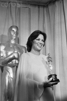 an old black and white photo of a woman holding her oscar award in front of statues