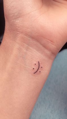 a small wrist tattoo with a smiley face on the left side of the wrist,