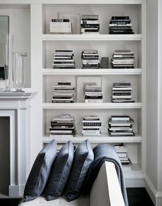 a living room filled with lots of furniture and bookshelves next to a fire place