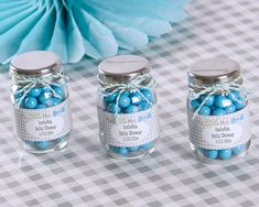 three glass jars filled with blue candies on top of a checkered table cloth