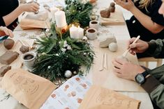 people are sitting at a table with paper decorations and candles on it, making crafts