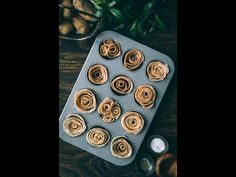 a muffin pan filled with rolled up doughnuts on top of a wooden table