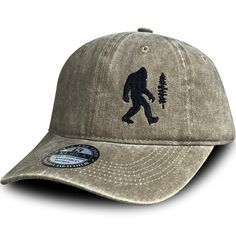 a bigfoot hat with the silhouette of a man holding a pine tree on it