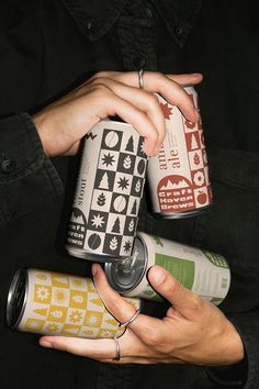 two people are holding cans of different types of drinks in one hand and an empty can on the other