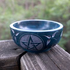 a blue bowl sitting on top of a wooden table next to some trees and bushes