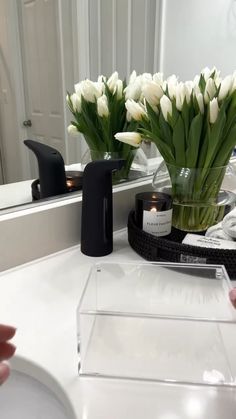 flowers in a clear vase sitting on a bathroom counter