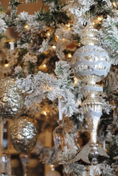 the christmas tree is decorated with silver and white ornaments