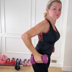 a woman holding two pink dumbs while standing in front of a row of exercise balls