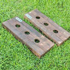 two pieces of wood sitting on top of green grass next to holes in the ground