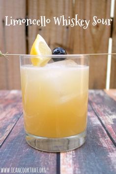 a glass filled with lemon and blueberries sitting on top of a wooden table