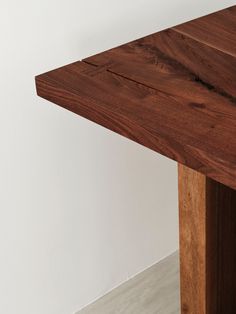 a close up of a wooden table against a white wall