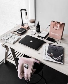 a white desk topped with a laptop computer next to a pink bag and other items