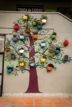 a tree with many pots on it painted on the side of a building