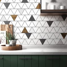 a kitchen counter with green cabinets and white tiled backsplash, potted plant on cutting board