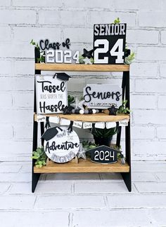 three tiered shelves with signs and plants on them in front of a white brick wall