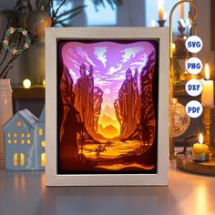 an image of a paper cut scene in a frame on a table with candles around it