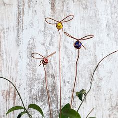 three metal dragon sculptures sitting on top of a white wooden table next to green plants