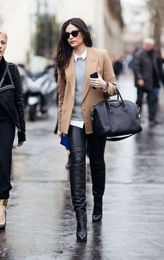 a woman is walking down the street with her hand in her pocket and holding an umbrella