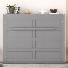 a gray dresser with some plants on top of it and a clock in the background